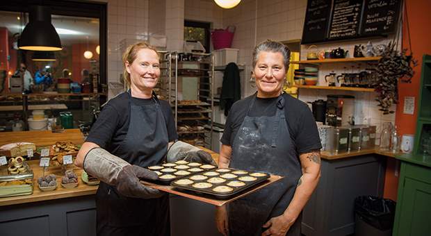Två kvinnliga bagare som håller en plåt.
